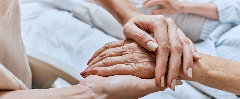 pflegerin hält hand von alter frau im bett