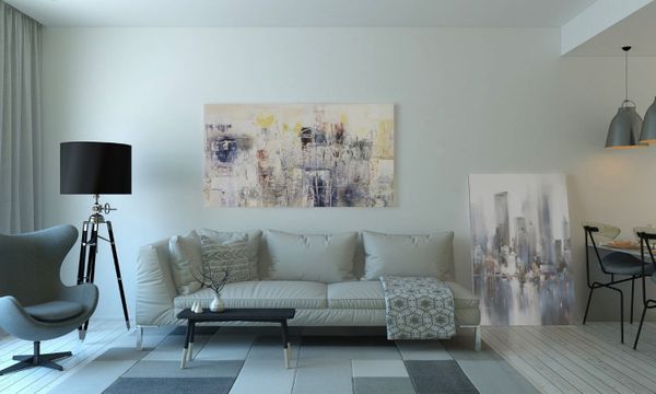 Wohnzimmer mit Couch, Bildern, Sessel, Lampe und Couchtisch