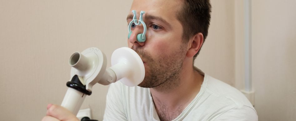 Mann atmet in Spirometer