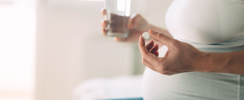 Schwangere mit Tablette und Wasserglas
